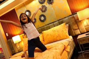 a little girl jumping on top of a bed at The Panorama Penthouse Daraga in Locsin