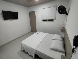 Habitación blanca con cama y TV de pantalla plana. en HOTEL MAR DEL CARIBE, en Soledad