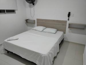 Cama blanca en habitación blanca con suelo blanco en HOTEL MAR DEL CARIBE, en Soledad
