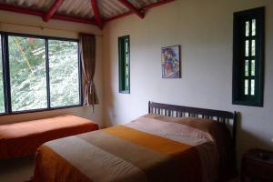 a bedroom with two beds and two windows at Alejandría, reserva natural y las 7 cascadas in La Vega