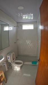 a white bathroom with a toilet and a sink at Coral Inn Providencia Isla in Providencia