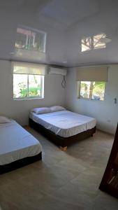 two beds in a room with two windows at Coral Inn Providencia Isla in Providencia