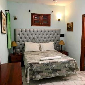 a bedroom with a large bed with a tufted headboard at Hotel Aluge in Santo Domingo