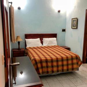 ein Schlafzimmer mit einem Bett mit einer karierten Decke in der Unterkunft Hotel Aluge in Santo Domingo