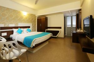 a hotel room with a bed and a television at moriz inz in Mysore