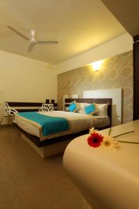 een slaapkamer met 2 bedden en een tafel met een bloem erop bij moriz inn in Mysore
