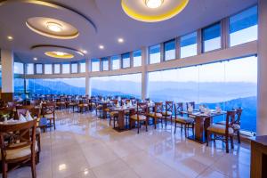 a restaurant with tables and chairs and a large window at Himalaya Drishya Resort in Dhulikhel