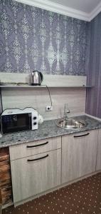eine Küchentheke mit Mikrowelle und Spüle in der Unterkunft Status House in Fargʻona