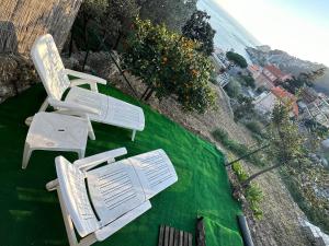 two white chairs sitting on top of a green lawn at Casa del sasso in Bergeggi