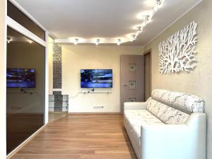 een woonkamer met een witte bank en een tv bij 2-х комн квартира с двухместным джакузи in Petropavlovsk