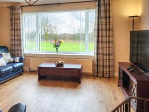 a living room with a couch and a window at Seven Seasons in Caldercruix