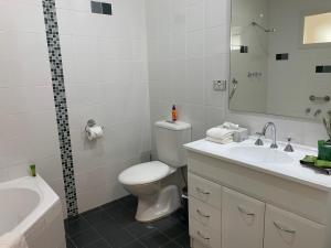 a white bathroom with a toilet and a sink at Pelicans Rest Shellharbour in Shellharbour