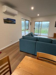 a living room with a blue couch and a table at Shell Cottage in Coles Bay