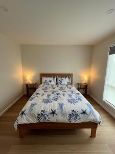 a bedroom with a bed with a blue and white comforter at Shell Cottage in Coles Bay