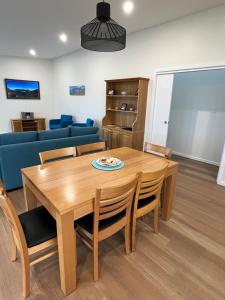 sala de estar con mesa de madera y sofá azul en Shell Cottage en Coles Bay
