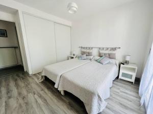 - une chambre blanche avec un grand lit et du parquet dans l'établissement Appartement Cambo-les-Bains, 2 pièces, 2 personnes - FR-1-495-14, à Cambo-les-Bains