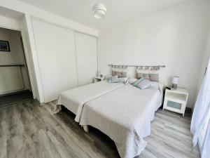 una camera da letto bianca con un letto grande e pavimenti in legno di T2 à Cambo-Les-Bains, balcon, parking privé, près des thermes - FR-1-495-14 a Cambo-les-Bains