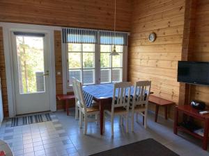 une salle à manger avec une table, des chaises et une télévision dans l'établissement Meri-Ruukin Lomakylä, à Matildedal