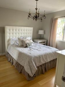 um quarto com uma grande cama branca e um lustre em Shabby chic abode in Los Angeles ca em Lomita