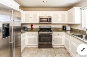 Una cocina con gabinetes blancos y un refrigerador de acero inoxidable. en Shabby chic abode in Los Angeles ca, en Lomita