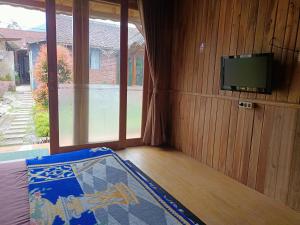 a room with a flat screen tv and a bed at ADK Papandayan Homestay & Tour in Tjisurupan