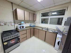 a small kitchen with a stove and a sink at Spacious & Comfortable 1 BR and 1 Living Room Apartment Near Sharjah University City in Sharjah