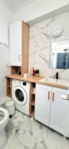 ein Badezimmer mit einer Waschmaschine und einem Waschbecken in der Unterkunft Apartament momA Oradea in Oradea