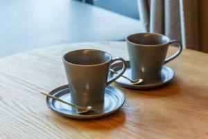 two coffee cups sitting on a wooden table at Amanecer Hotel in Tokyo