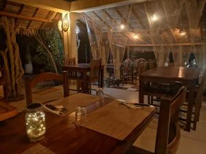 uma sala de jantar com mesas de madeira e cadeiras com luzes em Hotel Lakana Ramena em Antsiranana