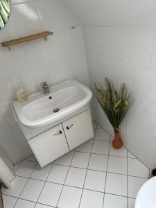 a white bathroom with a sink and a vase of flowers at KIosterlinchen in Walkenried