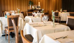 a dining room with white tables and chairs with glasses at Hotel Pergola in Legnago
