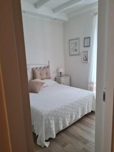 una camera bianca con letto bianco e cuscini rosa di La casetta del nonno a Capodimonte
