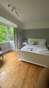 a bedroom with a white bed and a wooden floor at Meadowside Troutbeck Bridge, Windermere sleeps 5-6 in Windermere