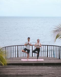 un homme et une femme faisant du yoga sur une jetée dans l'établissement The Kirana Tembok, à Tejakula