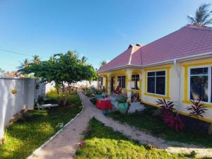 uma casa amarela com uma mesa no quintal em L&J Modern Backpackers Kigamboni Beach House em Dar es Salaam