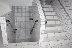een trap in een badkamer met witte tegels bij Cantinho Canadense in Praia Grande