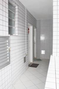 een wit betegelde badkamer met een douche en een deur bij Cantinho Canadense in Praia Grande
