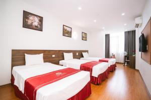two beds in a hotel room with white and red sheets at Thành An Hotel in Ha Long