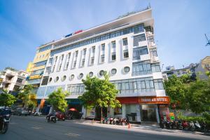 a large white building on a city street with motorcycles at Thành An Hotel in Ha Long
