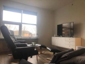 ein Wohnzimmer mit 2 Stühlen und einem TV in der Unterkunft Grønnegade - tæt på Esbjerg C in Esbjerg