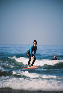 Un giovane uomo che cavalca un'onda su una tavola da surf nell'oceano di Arima Surf House a Tamraght Ouzdar