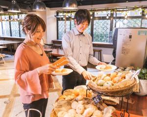 a man and a woman holding plates of food at HOTEL RELIEF Namba Daikokuchou in Osaka