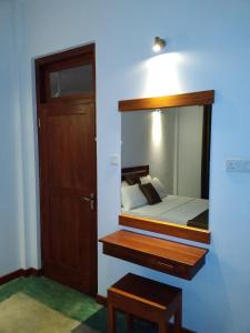 a bedroom with a bed with a mirror and a door at Yala wind in Tissamaharama