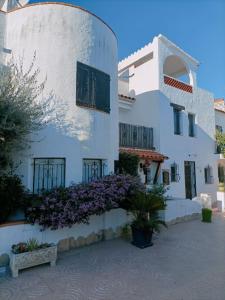 un edificio blanco con flores púrpuras delante de él en Maison 3 chambres proche plage amarre 7 m, en Empuriabrava