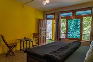 a bedroom with a bed and a table and windows at Whoopers Hostel Tosh in Tosh