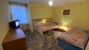 Habitación pequeña con 2 camas y TV. en Аria B&B, en Burgas