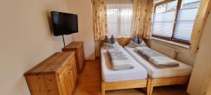 2 Betten in einem Zimmer mit einem TV an der Wand in der Unterkunft Appartement Gugganig in Flattach