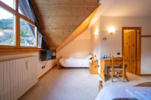 Habitación con cama, escritorio y ventana. en Fior di Roccia - Valmalenco - Hotel & Mountain Restaurant en Lanzada