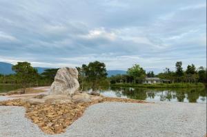 a large rock sitting on the side of a lake at Ravin Home ราวินโฮม in Nakhon Nayok