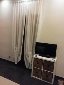 uma televisão de ecrã plano sentada numa bancada em frente às cortinas em Terrazza Roberto em Cefalù